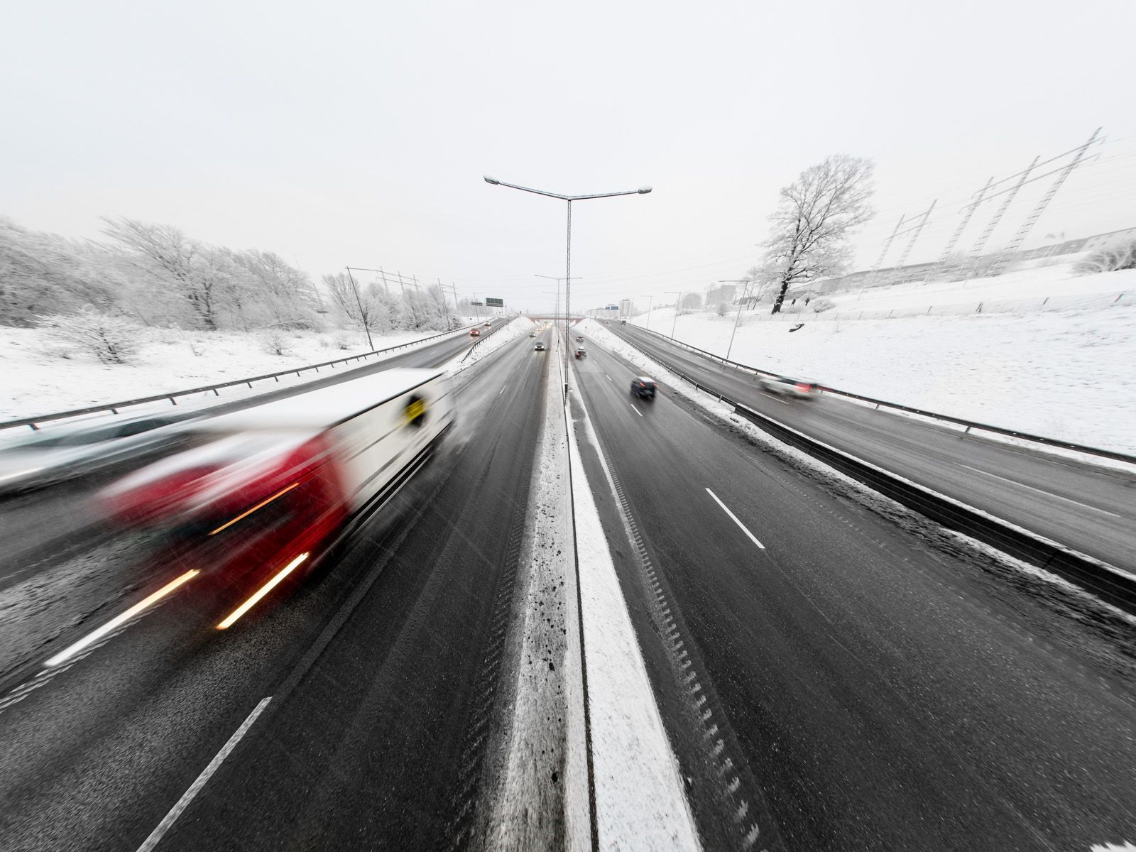 En motorväg med suddig traffik från rörelsen och lång exponering. Allt utom vägbanan är täckt av snö