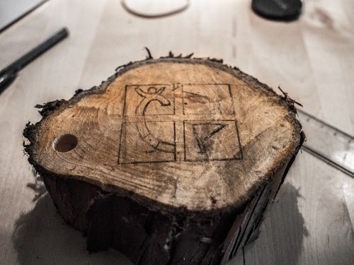 En tjock gren med en symbol för geocaching ritad med blyerts på änden