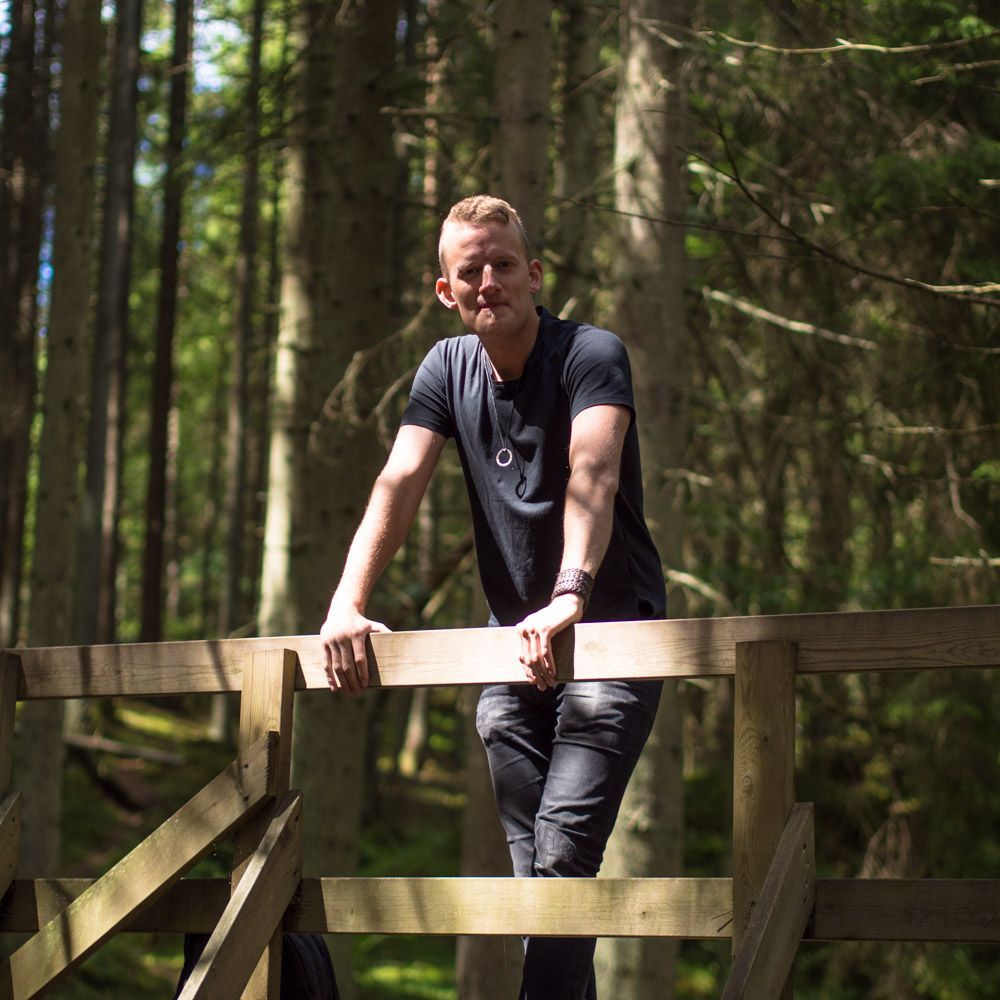 Marcus lutar sig på räcket på en bro i skogen.