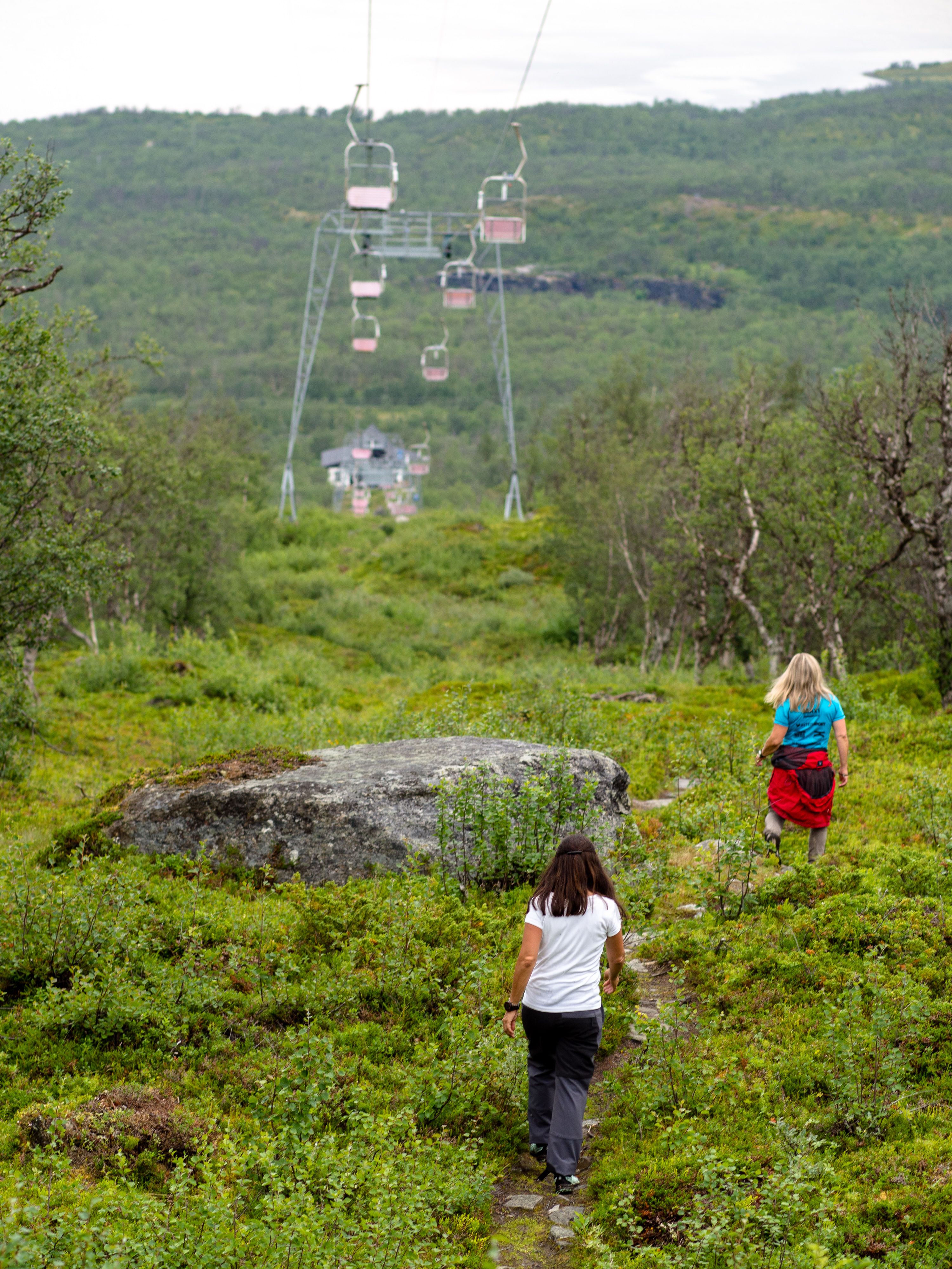 Två personer som går på en stig under en linbana