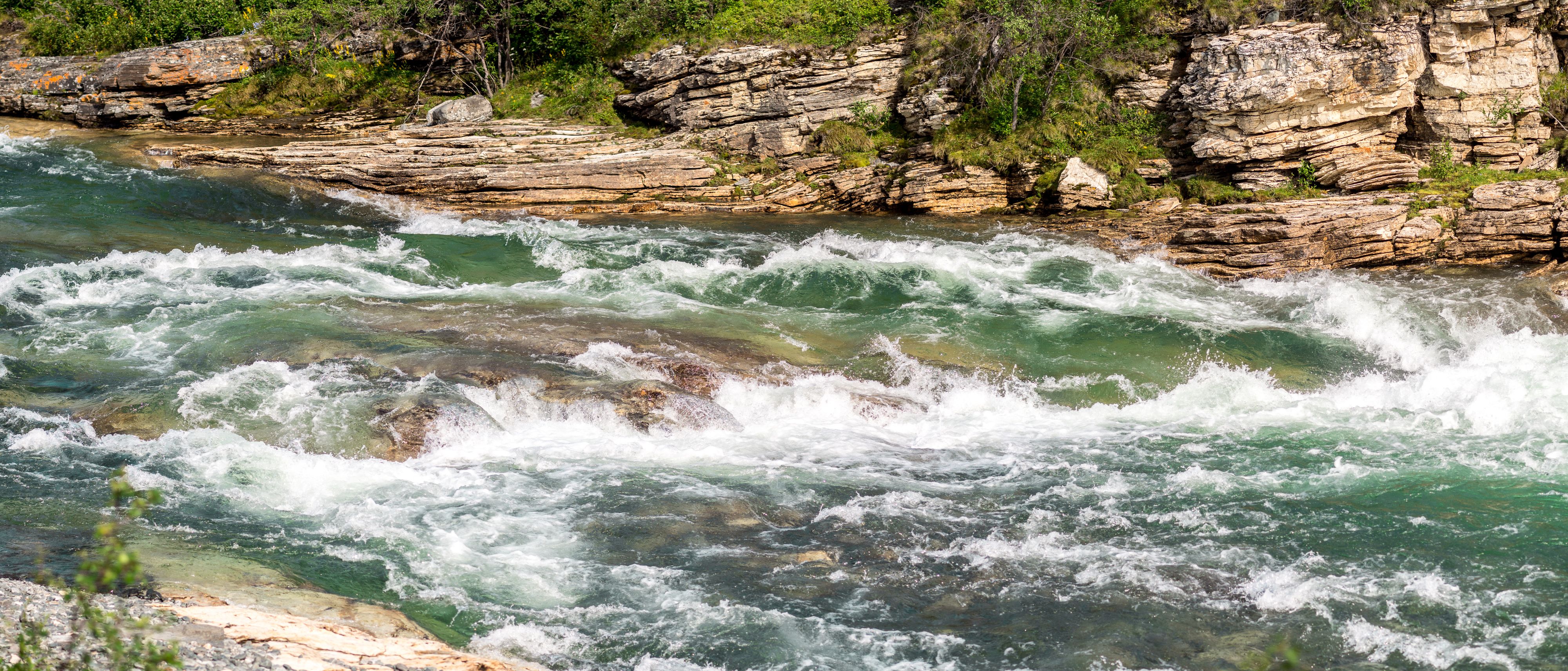 Närbild på en fors med grönt klart vatten