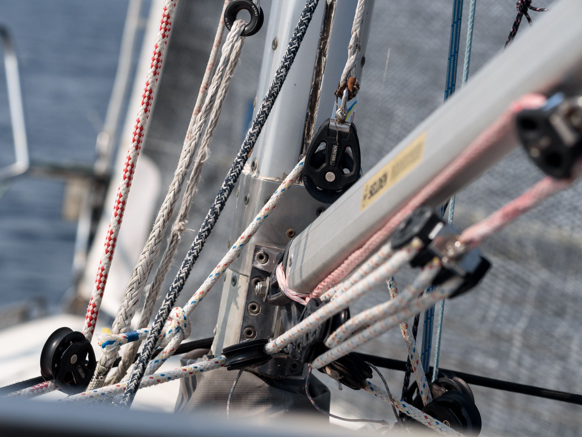 En närbild på bommen och nederdelen på masten på en segelbåt med alla tampar och fall.