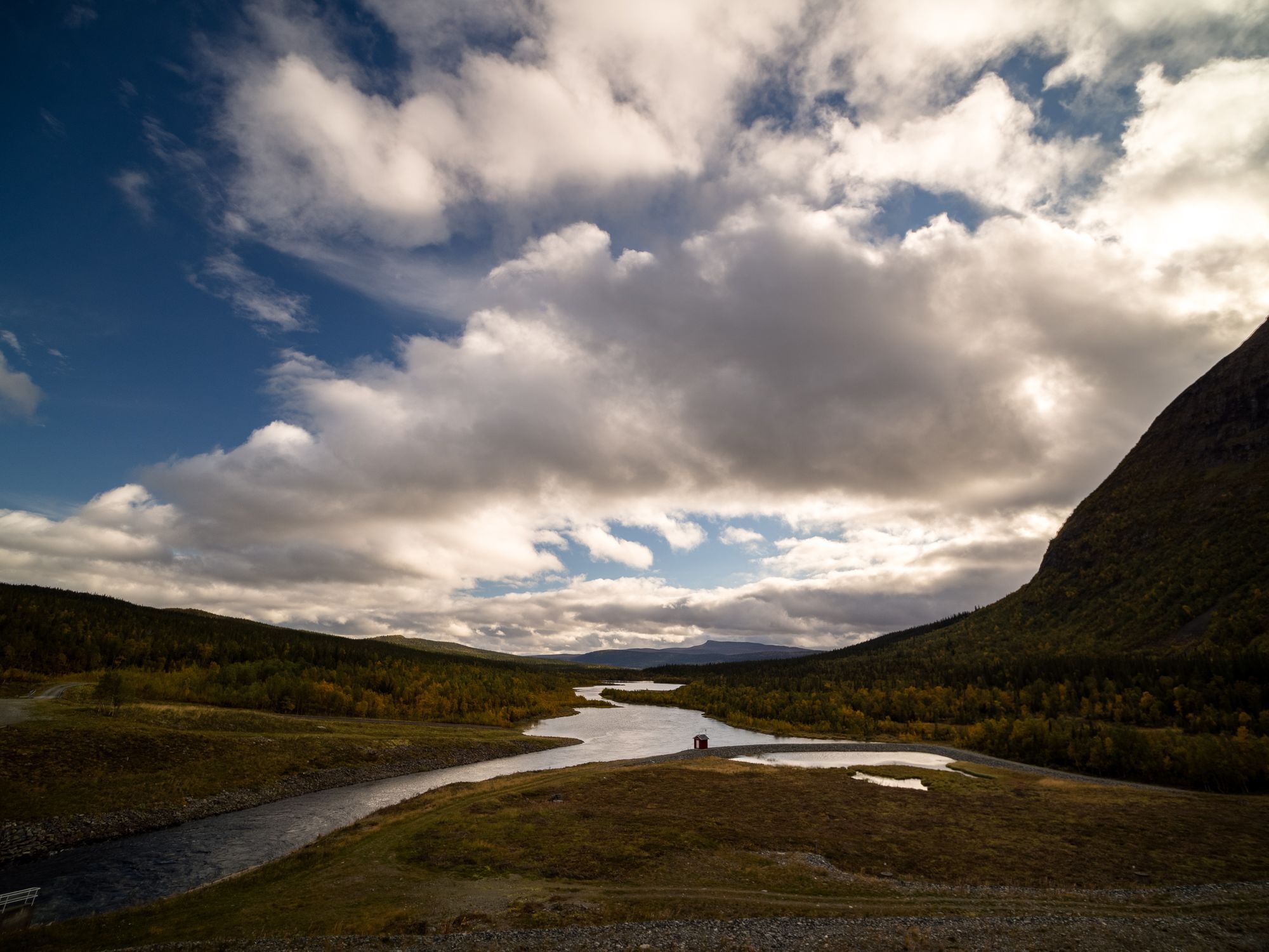En flod som rör sig genom ett fjälllandskapp. Till höger skymtas Borgafjäll