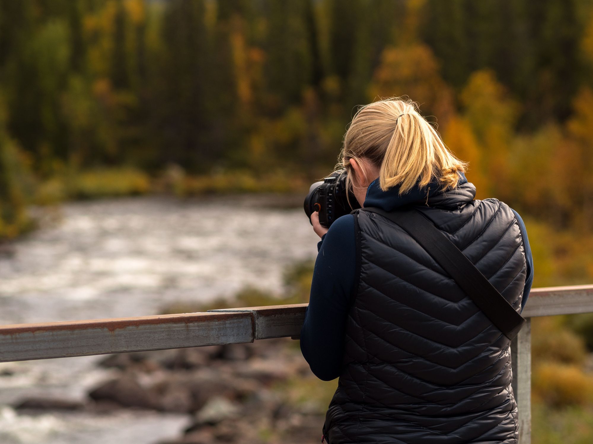 En person som fotograferar en flod från en bro.
