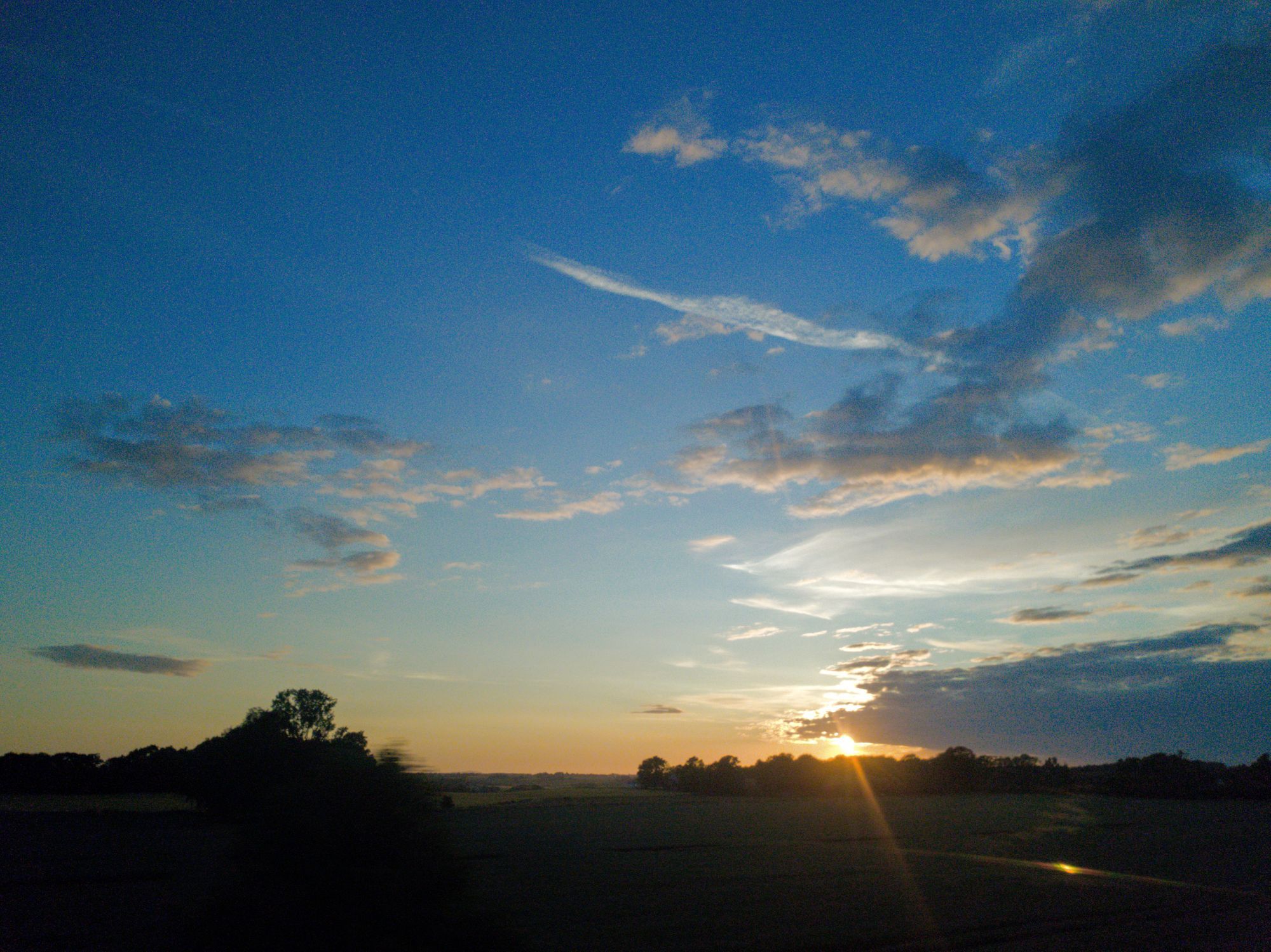 Solnedgång över öppna fält i Skåne.