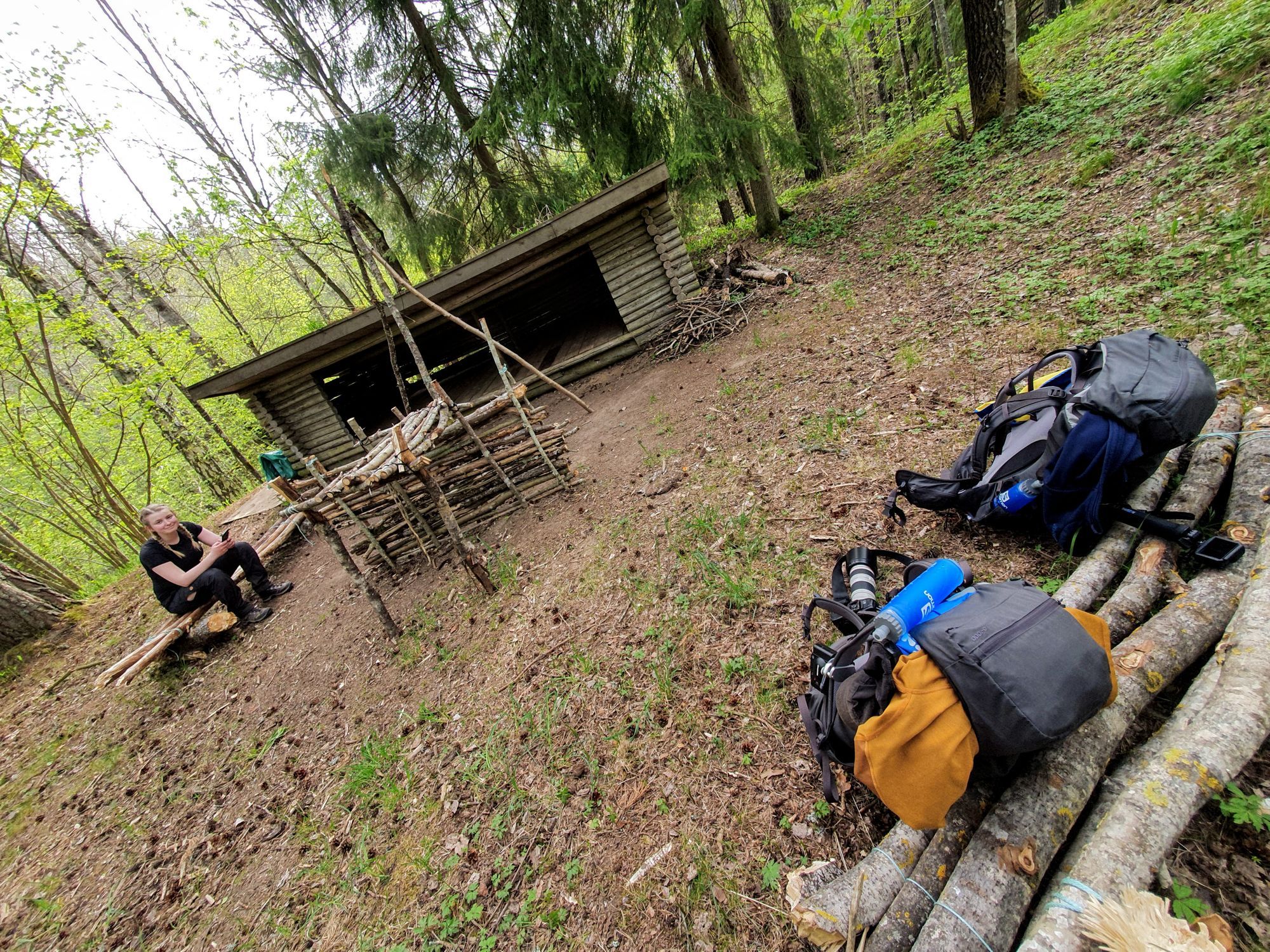 Två ryggsäckar som står lutade mot några pinnar intill ett vindskydd.