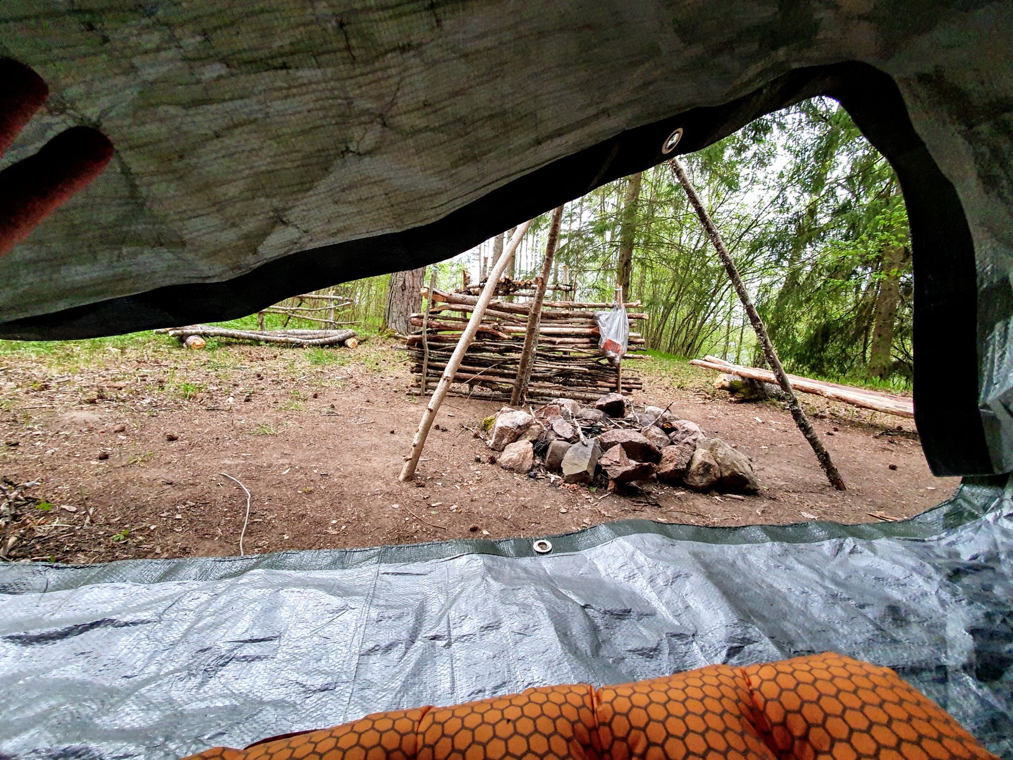 En eldstad sedd inifrån ett en presenning använd som ett regnskydd