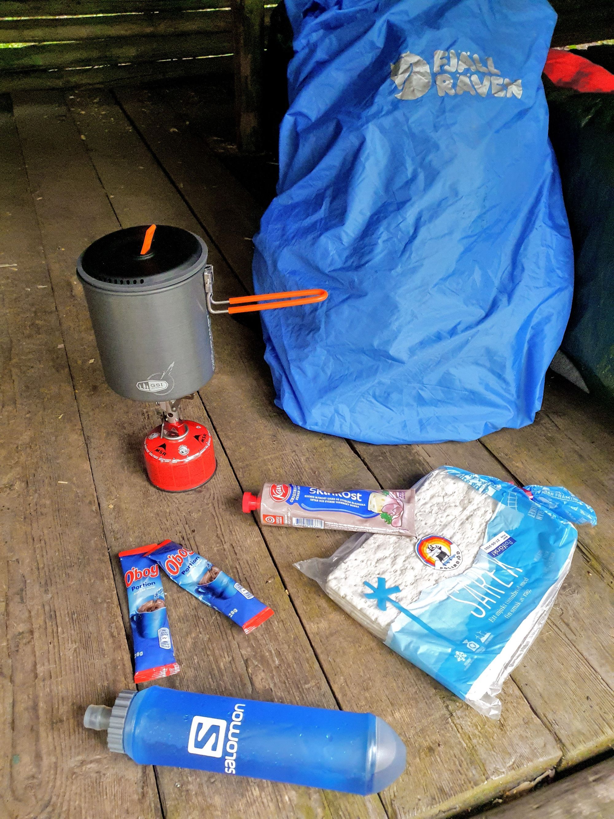 Tunnbröd med skinkost, oboyförpackningar och ett friluftskök som ligger på golvet i ett vindskydd