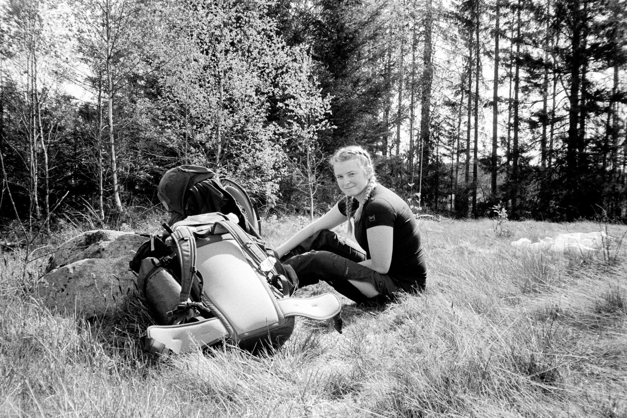 Josefine sitter i gräset bredvid sin ryggsäck