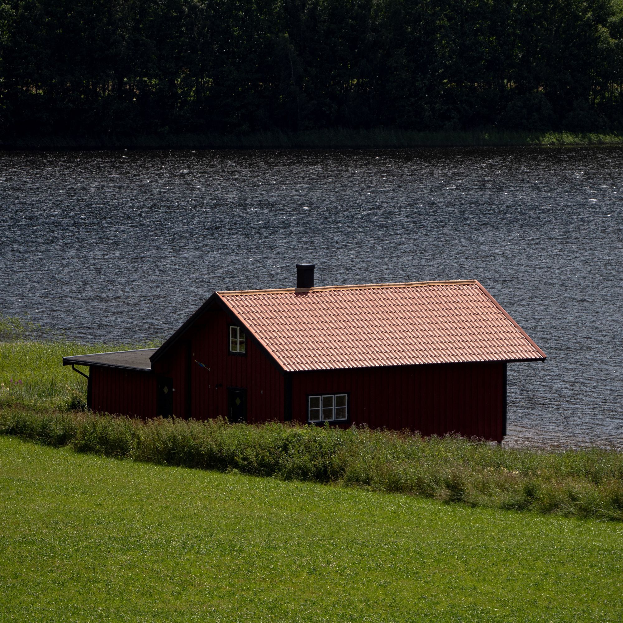 En röd stuga nere vid en sjö