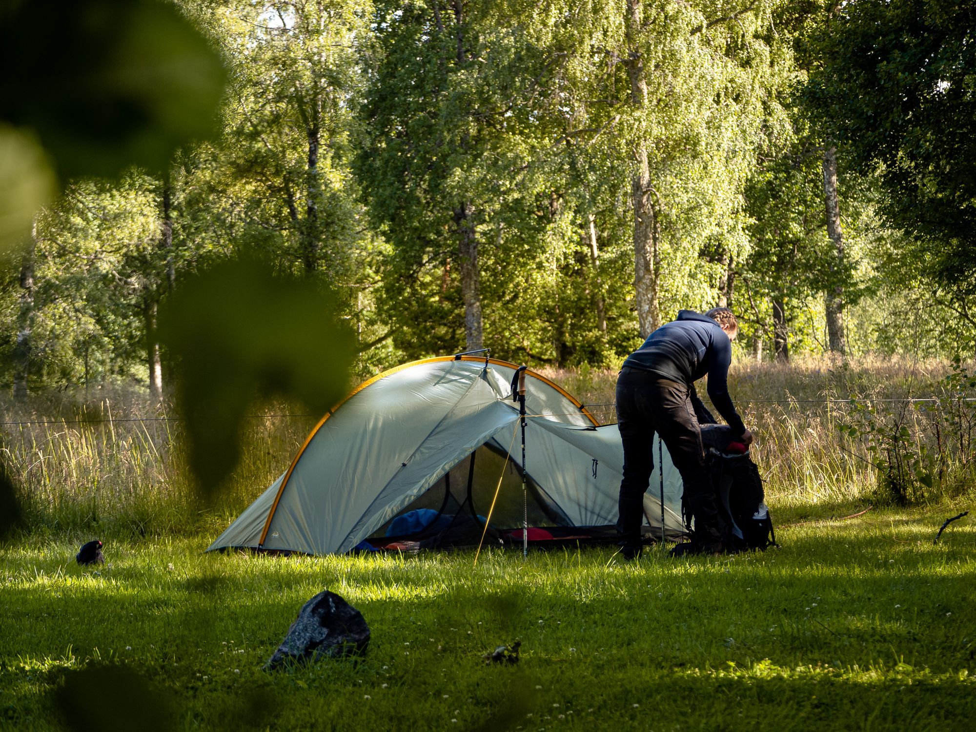 Josefine packar upp sin väska intill ett tält