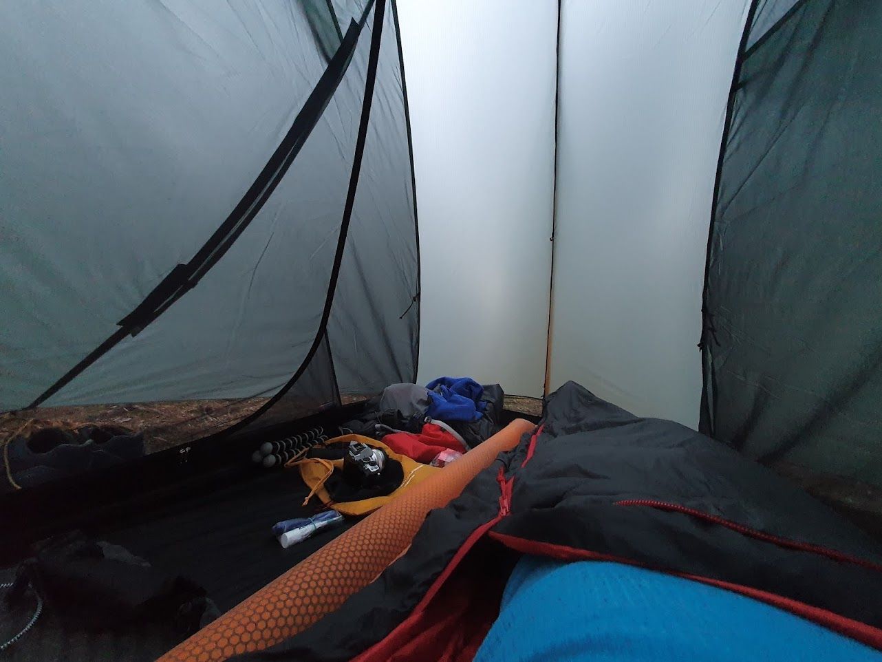 Insidan av ett tält från perspektivet av en person liggande på ett liggunderlag.