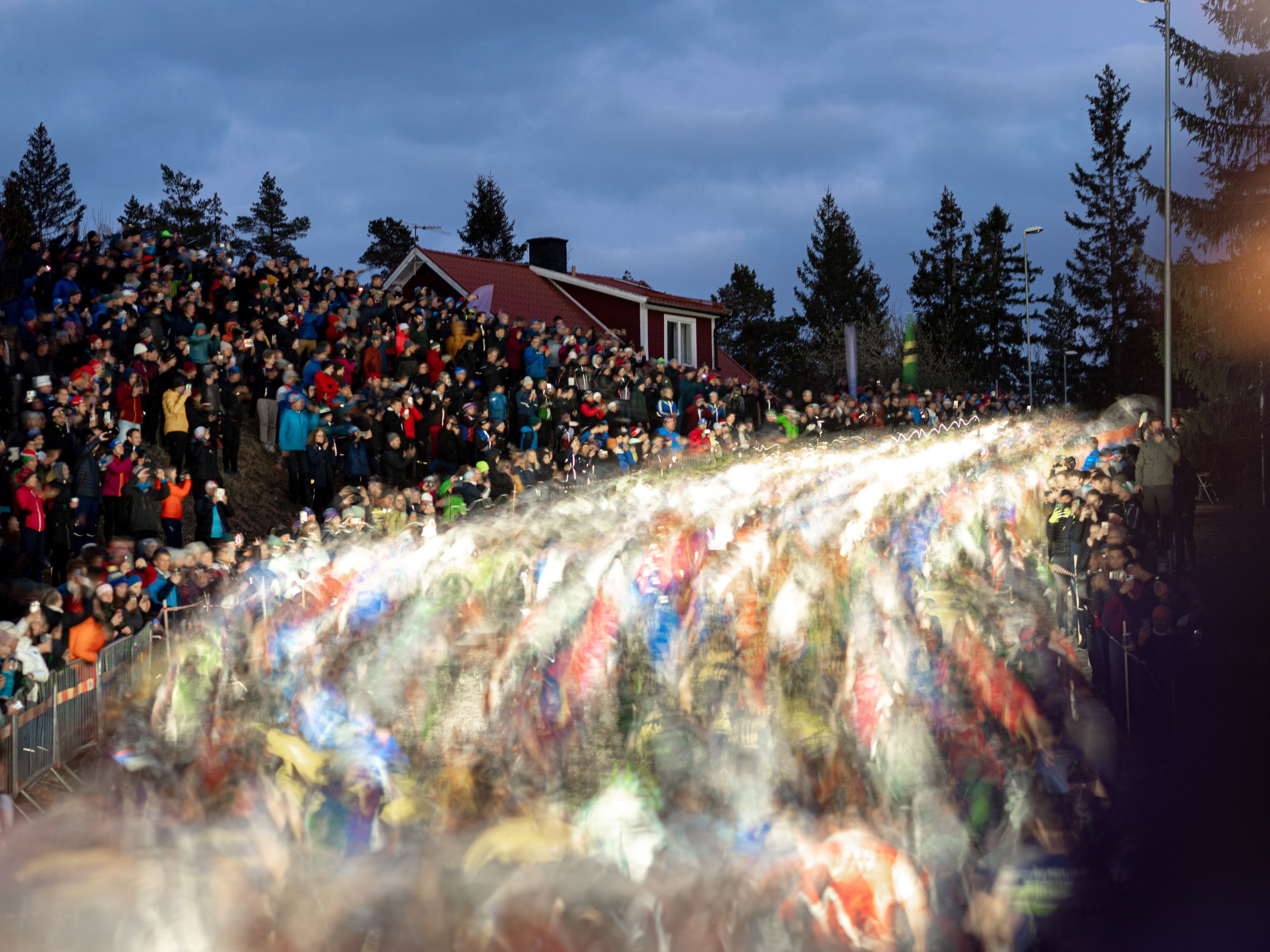 Lång exponering av hundratals orienterare som springer uppför en backe med pannlampor.