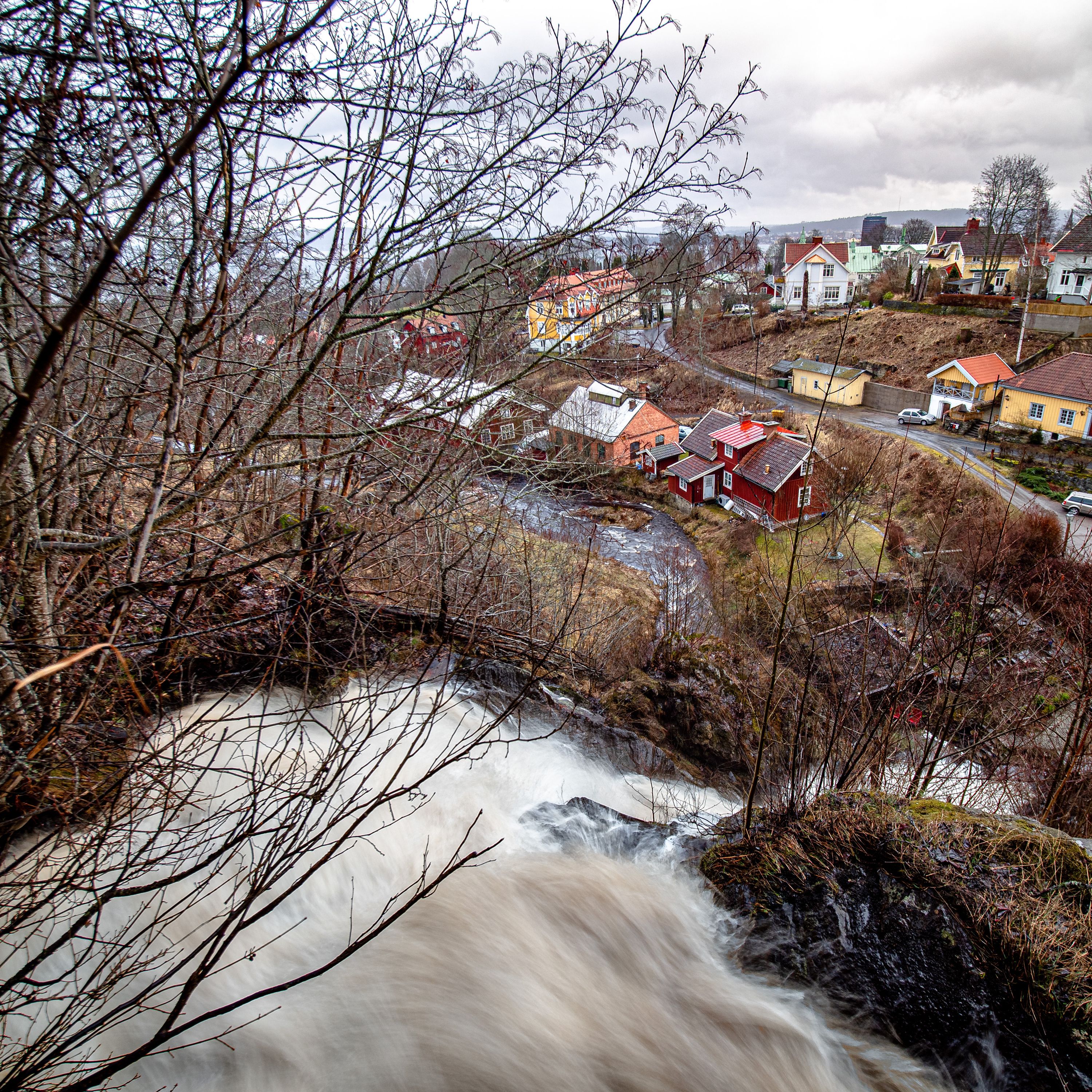 Utsikt från toppen av Dunkehallaravinen med vattenfallet för Dunkehallaån rakt nedanför i full kraft. Vättern och Jönköping skymtas en bit bort med regnmoln över.