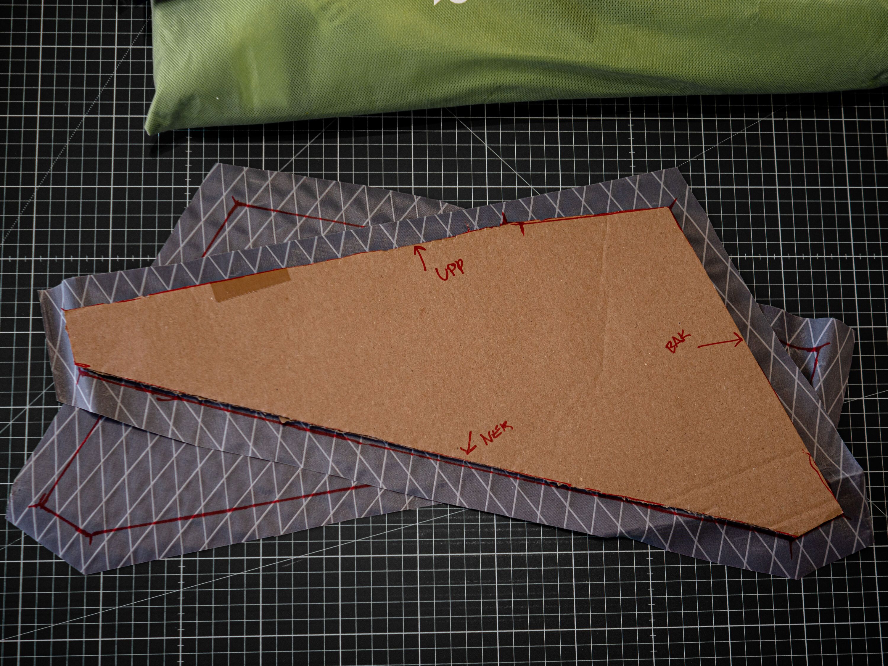 En mall av kartong som ligger påe n utklippt tygbit