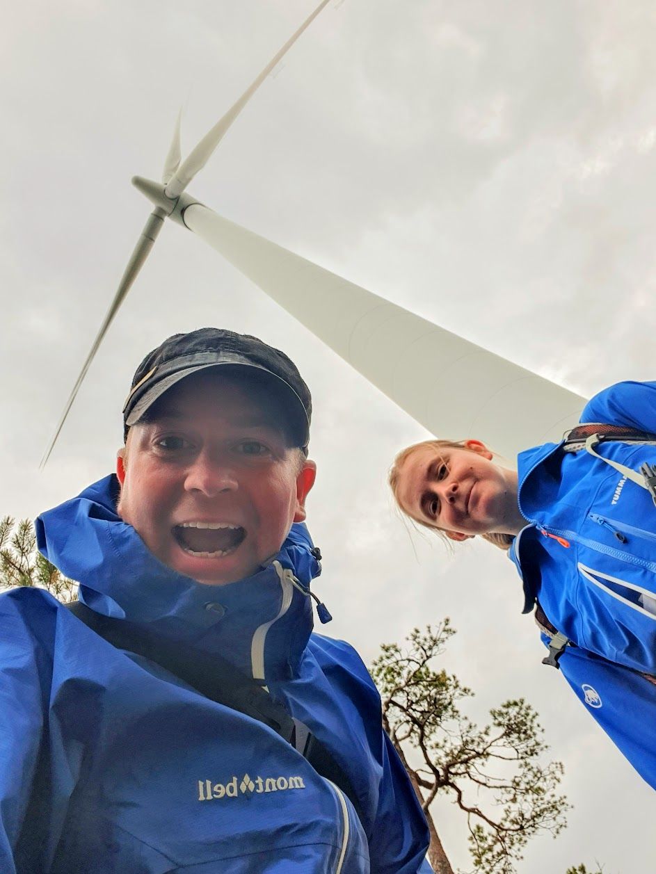 Två personer som ser väldigt glada ut under ett vindkraftverk