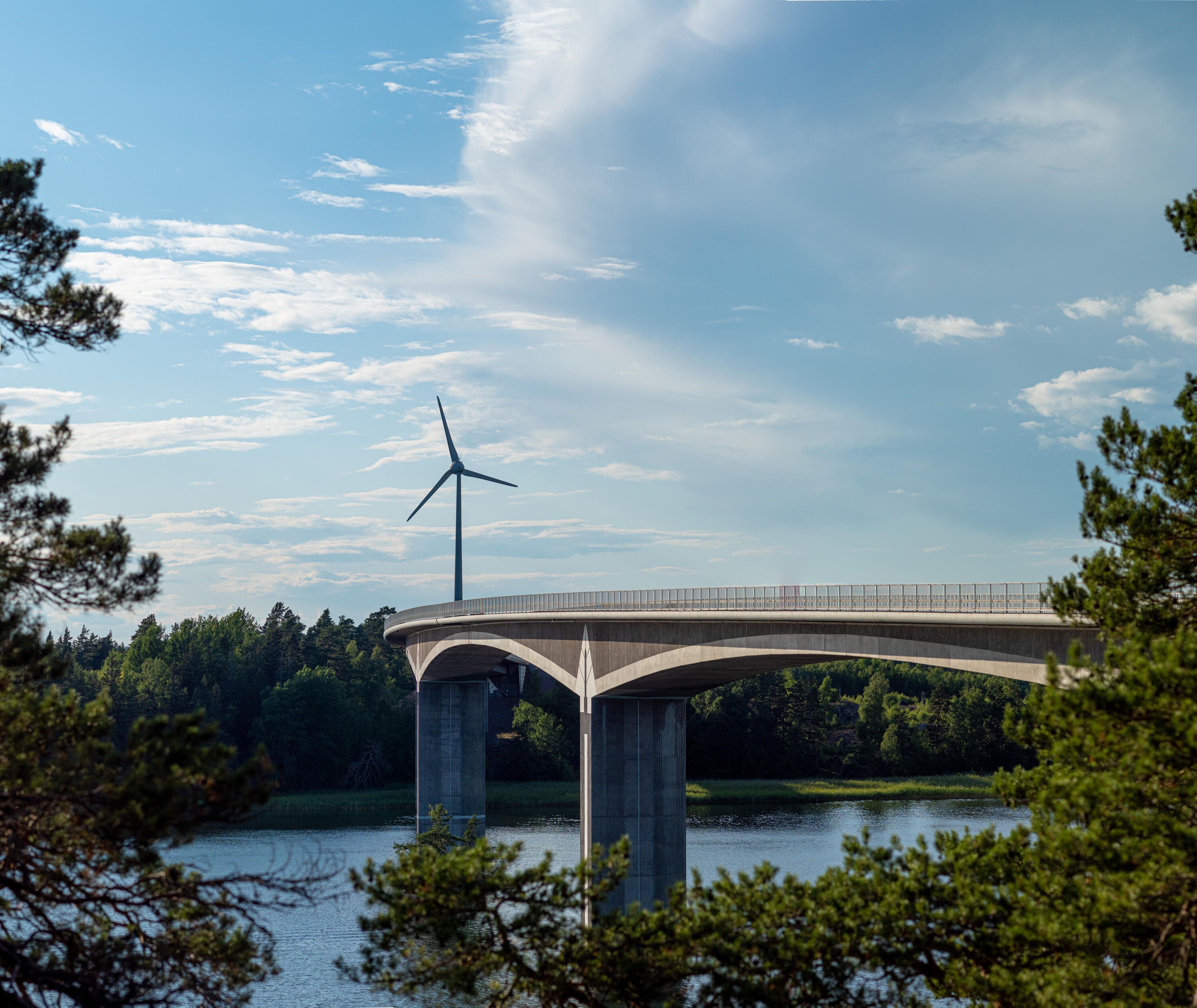 En bro med skog och ett vindkraftverk bakom