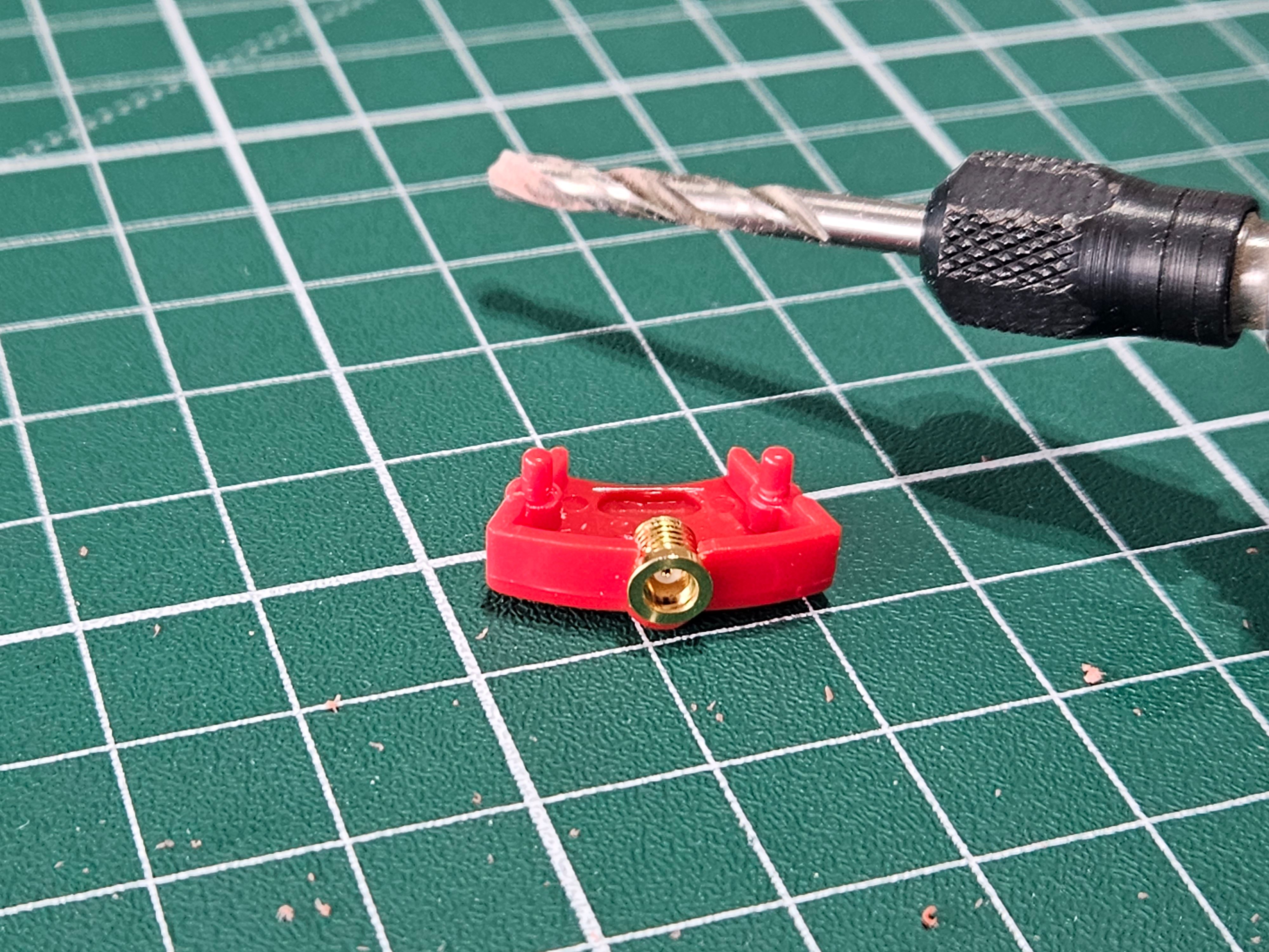 En del från ett par Koss Porta Pro med en MMCX-koppling i. Bredvid syns ett borr på en dremel.