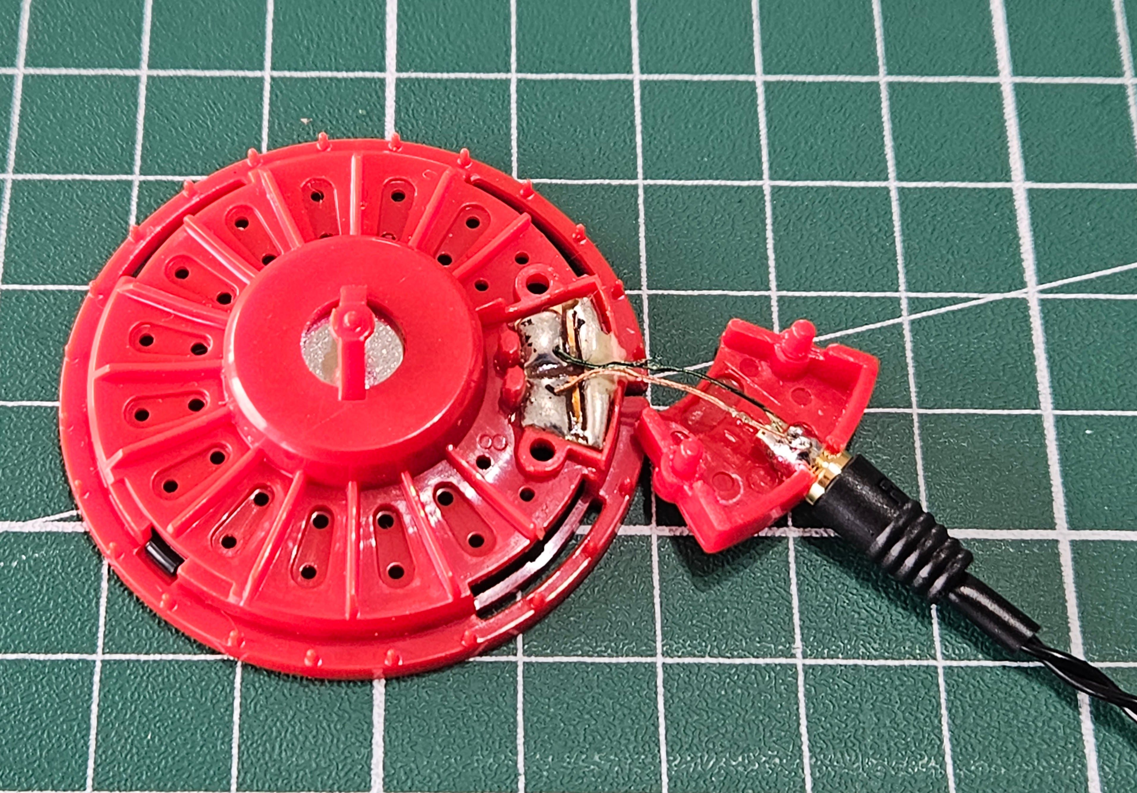 Ett element från en Koss Porta Pro med två kablar fastlödda på en MMCX-koppling.