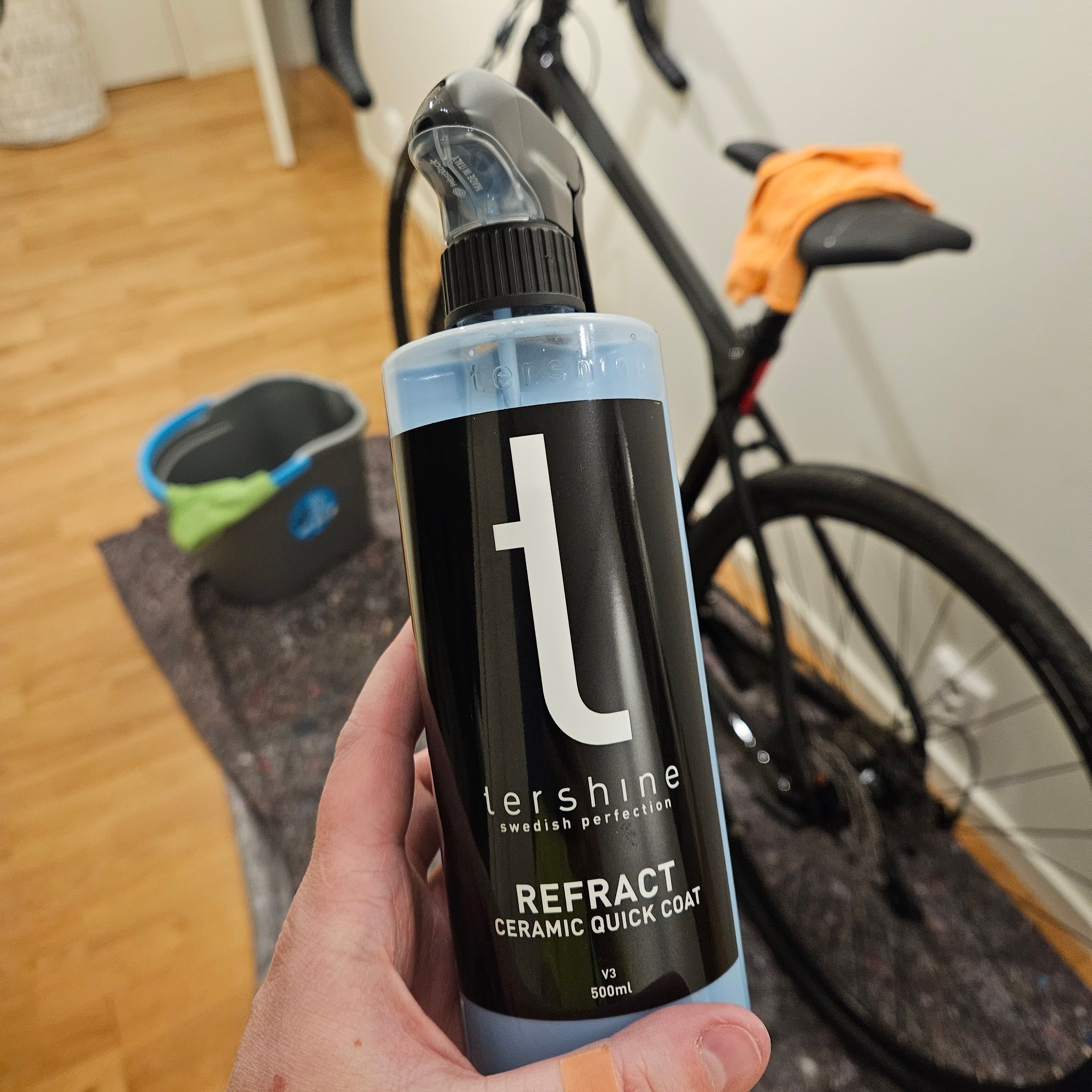 En förpackning Tershine Refract lackskydd med en cykel i bakgrunden ur fokus.