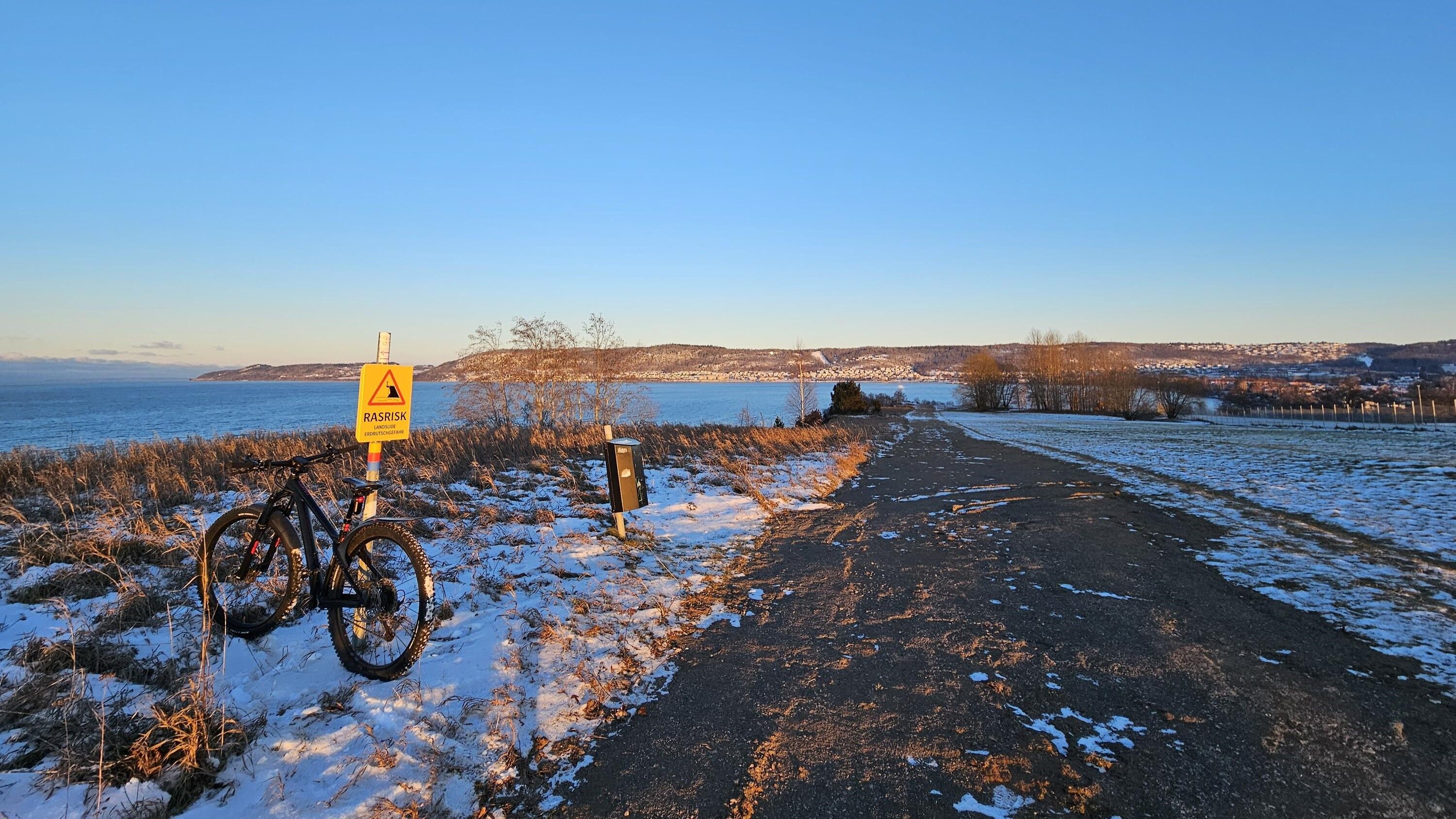 Rosenlunds bankar i snö. Det står en cykel som lutar sig mot en skylt som det står Rasrisk på