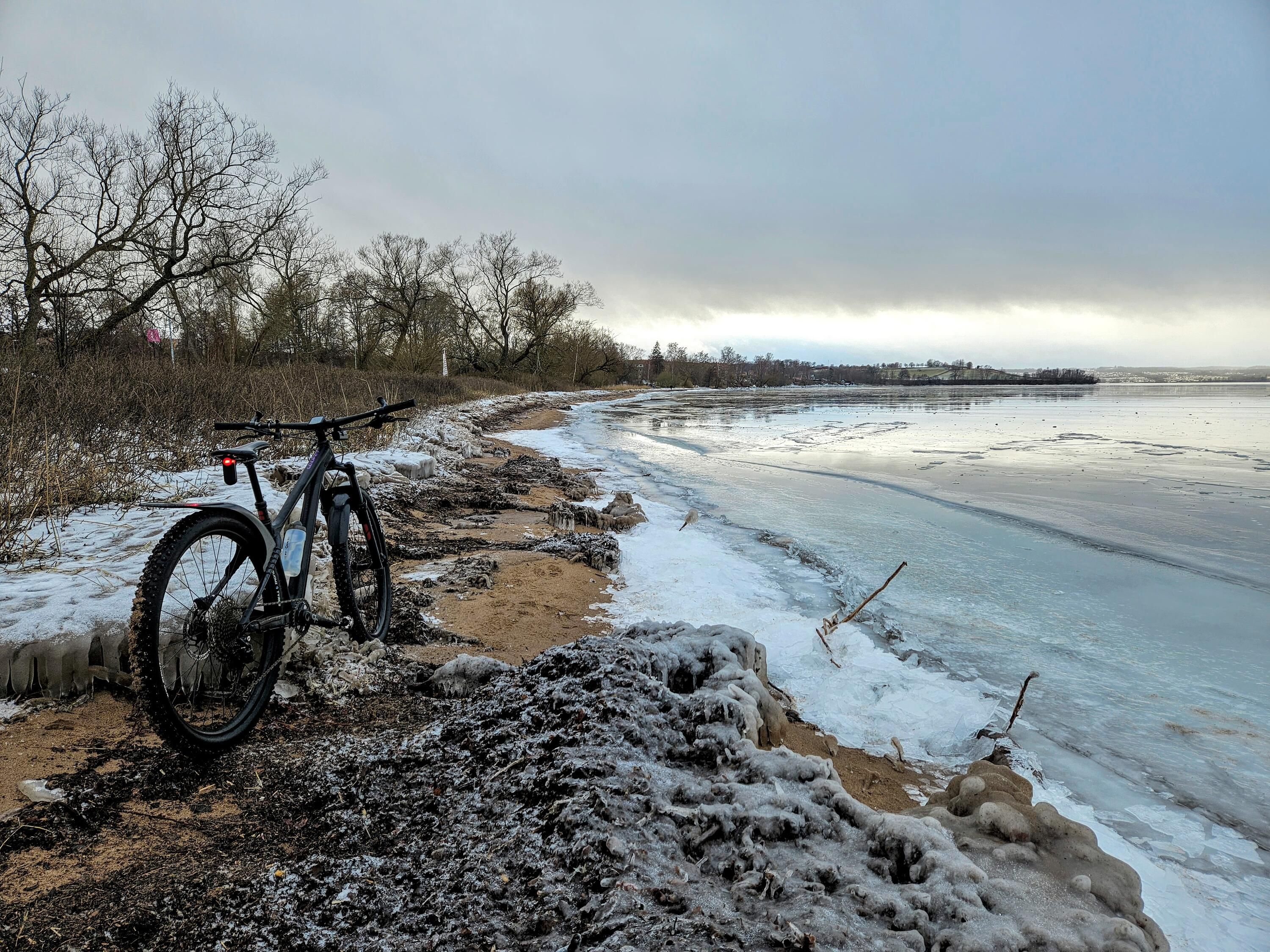 En cykel som står lutad på en isig strand.