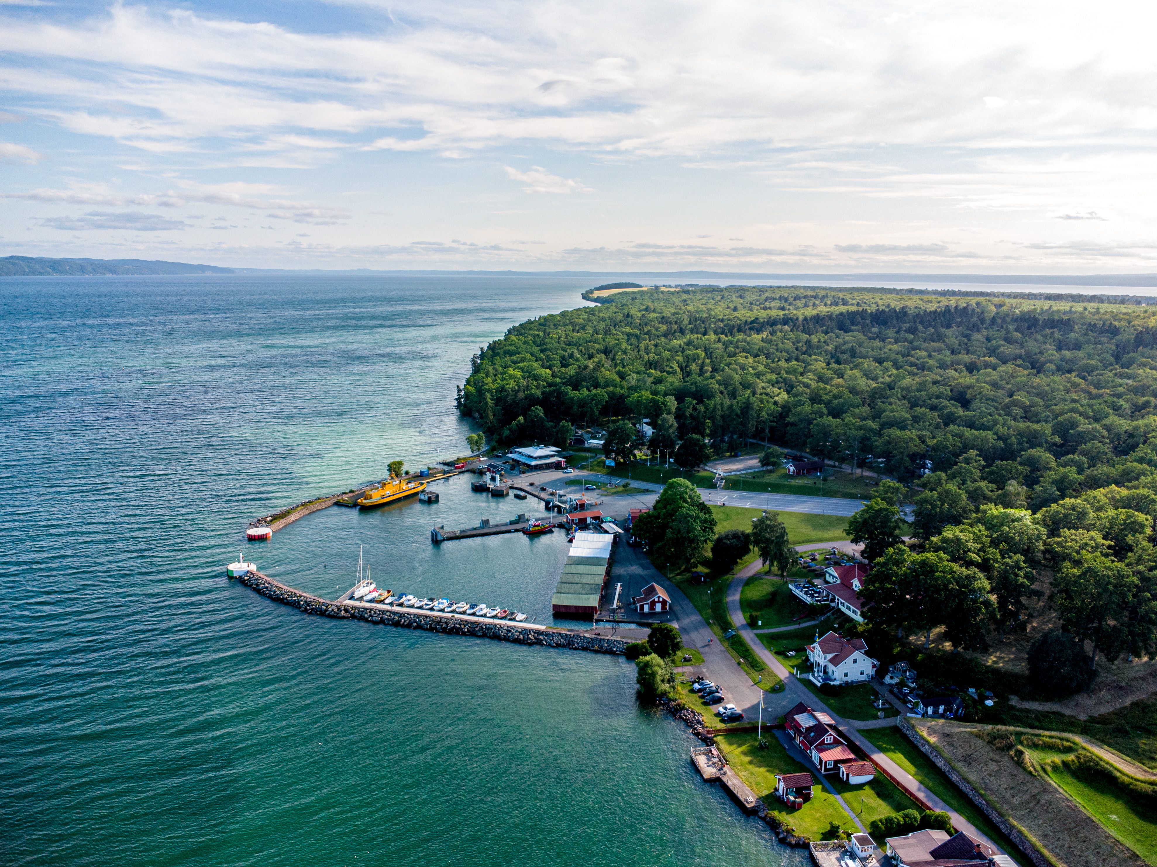 Flygfoto över hamnen på Visingsö med Vättern i bakgrunden under en blå himmel