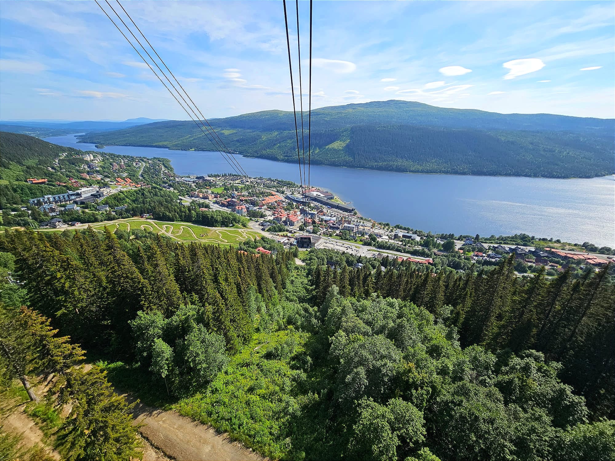Vy från en kabinbana ner mot en stad intill en älv.