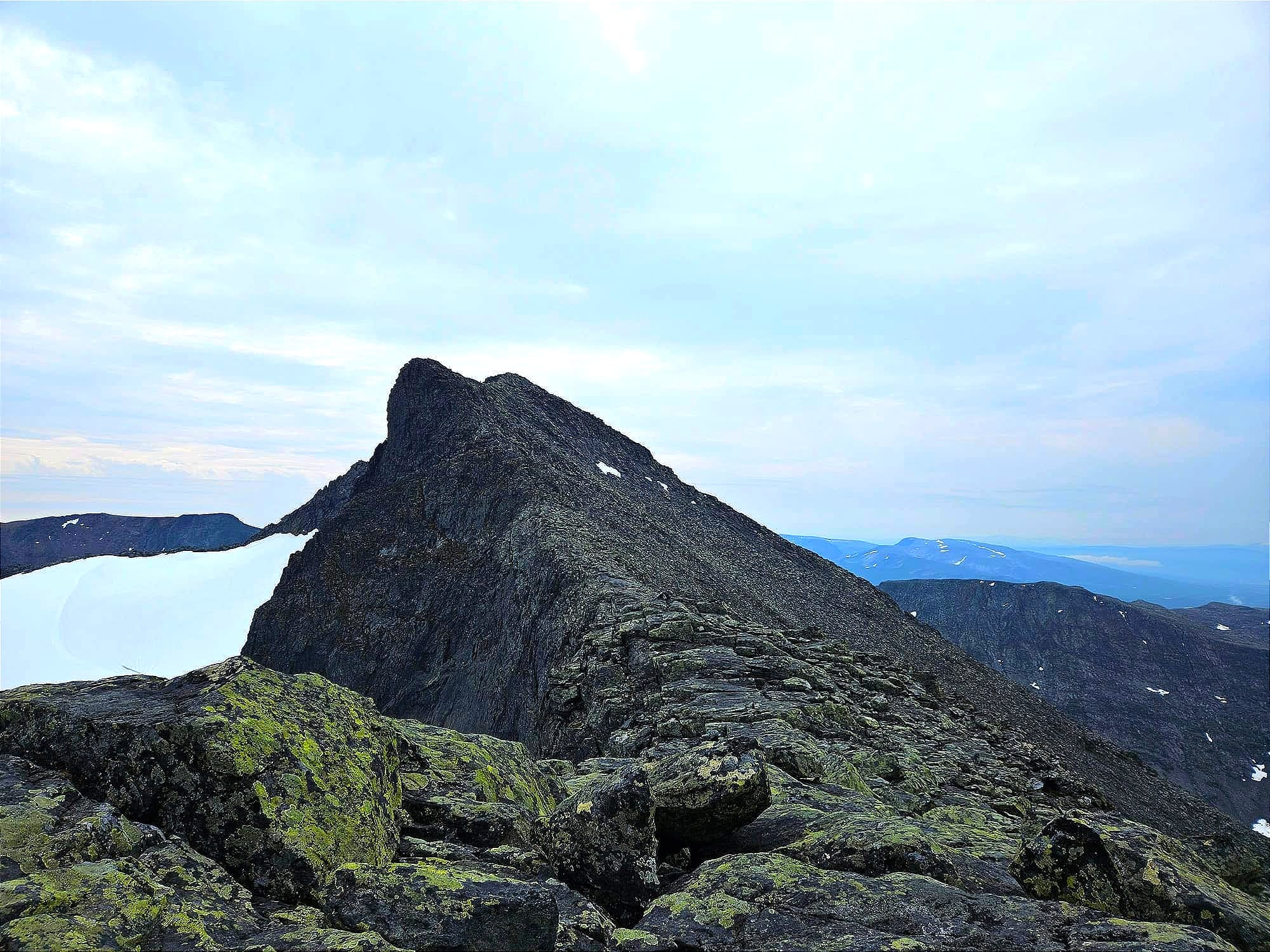 En stenig brant bergstopp sedd från sidan. Ena sidan stupar rakt ned, andra sidan av toppen lutar runt 45°