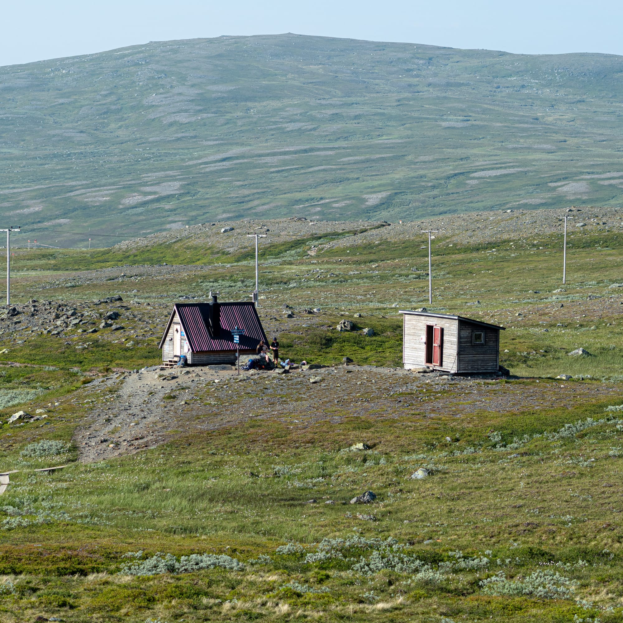 En raststuga och ett utedass i ett stenigt fjällandskap.