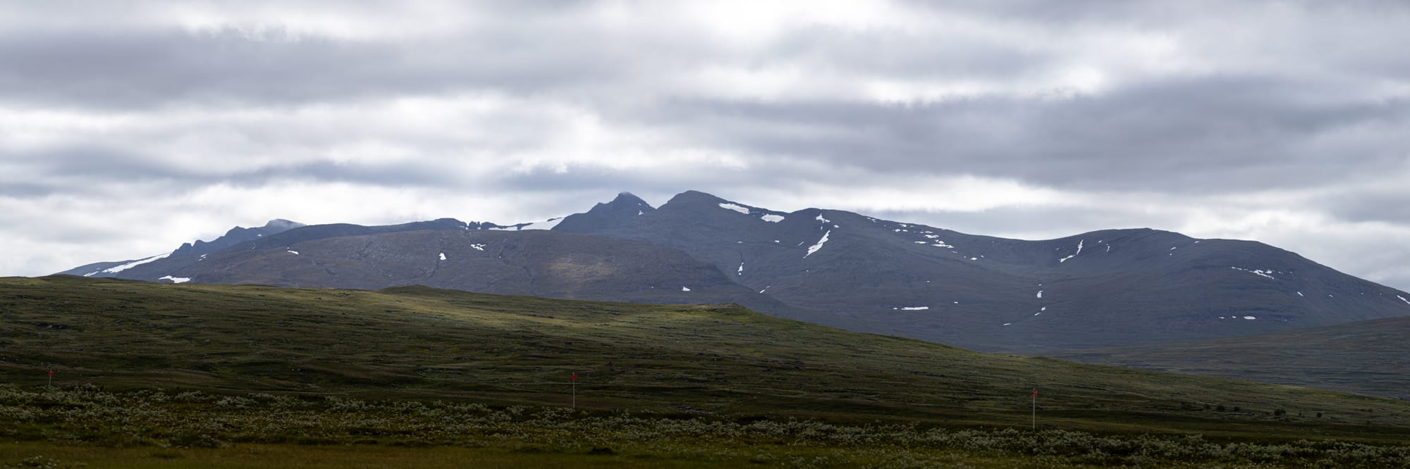 En alpin bergskedja i fjärran med moln som täcker toppen